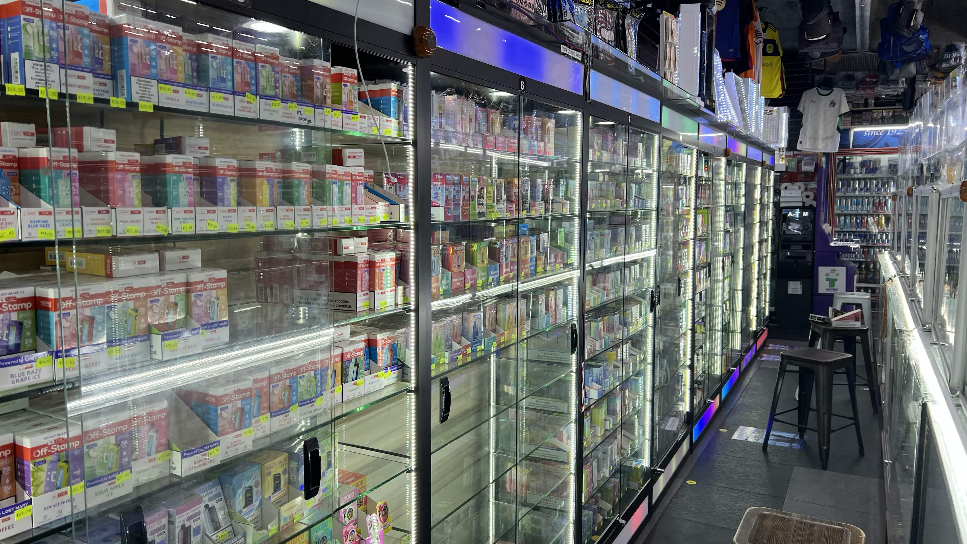 Floor-to-ceiling lit glass cases of disposable vapes and e-cigs inside Tobacco Brew & Chew